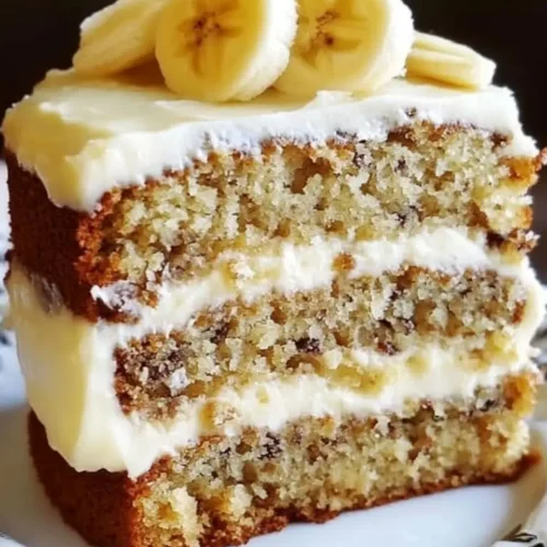 A slice of Banana Bread Cake with Cream Cheese Frosting and banana slices on top