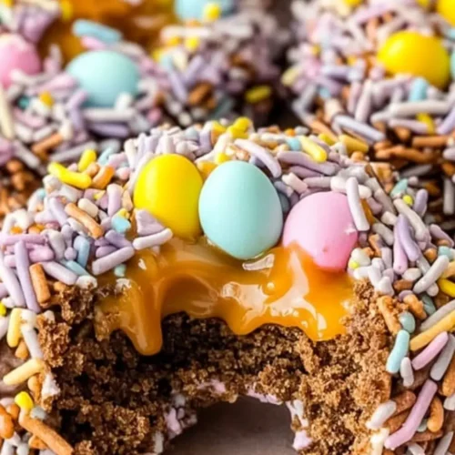 A close-up of a festive chocolate bird’s nest cookies with colorful candy eggs and caramel filling.