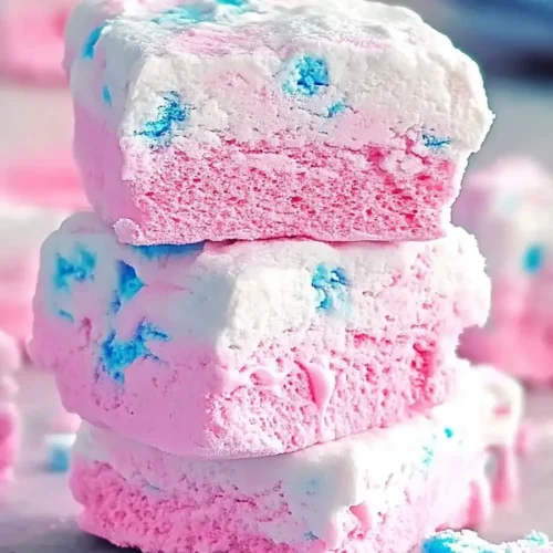 Easy Cotton Candy Marshmallows with blue swirls, stacked in a pastel-themed setting.