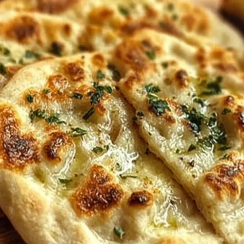 Warm Garlic and Butter Flatbread with golden spots, glistening melted butter, and fresh herbs sprinkled on top
