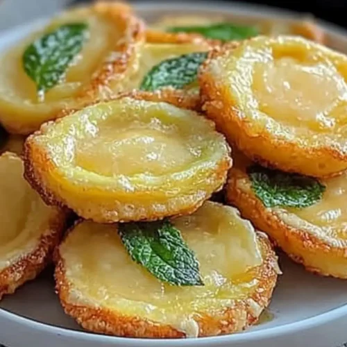 Crisp, Golden Twice-Fried Tostone Crunchies stacked on a plate, glistening with a light sprinkle of salt and served with a side of dipping sauce.