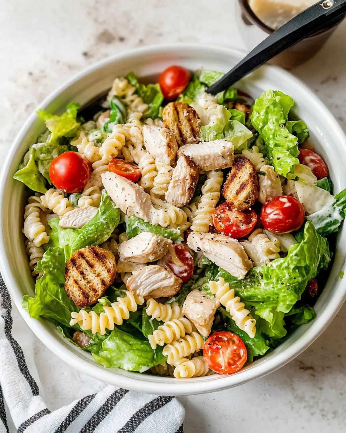 chicken caesar pasta salad recipe Bowl of Chicken Caesar Pasta Salad with grilled chicken, rotini pasta, romaine lettuce, and cherry tomatoes tossed in creamy Caesar dressing.